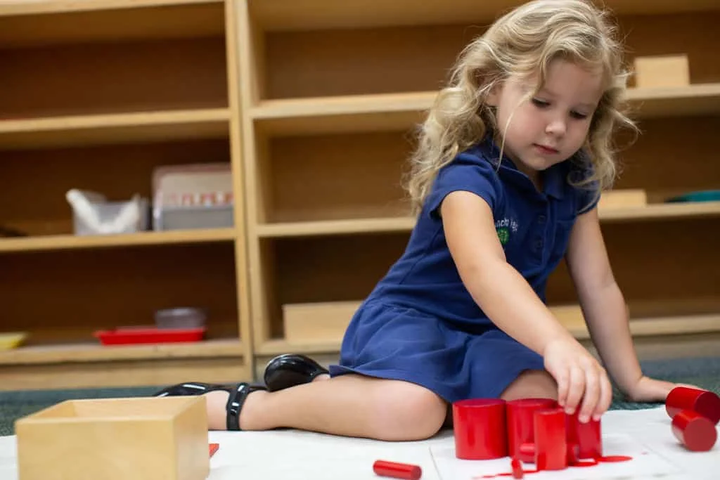 A child working independently with red Montessori materials